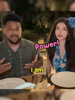 A shot featuring a man and a woman seated at a table. The man, on the left, is gesturing with his hands while speaking, while the woman on the right is looking directly at the camera. Text overlays saying 'Power!' and 'I am' are added on the image.