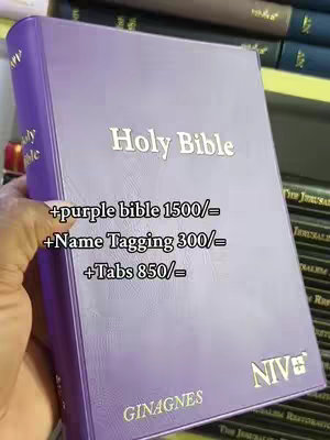 The image shows a purple bible held by a hand, with text overlayed, detailing the pricing for the bible and additional name tagging and tabs.