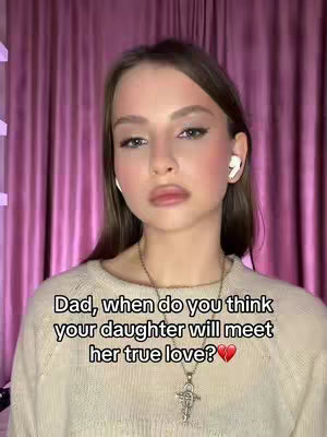 A young woman in a beige sweater gazes at the camera against a backdrop of pink curtains. The image has a soft focus, emphasizing her face and the text overlay at the bottom.