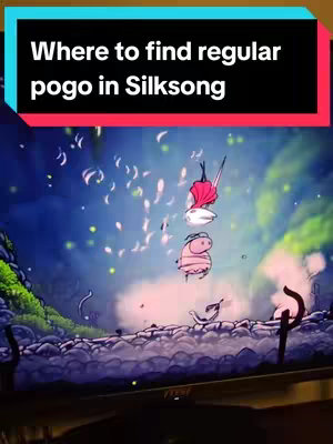 The cover image is a vertical shot of a video game scene displayed on a monitor. The scene is a stylized, imaginative landscape with a cloudy, blue sky. In the center, animated characters, seemingly in mid-air, are the visual focus: a character with a red cape above, and a pink insectoid figure below. The text overlay is a colored rectangle.
