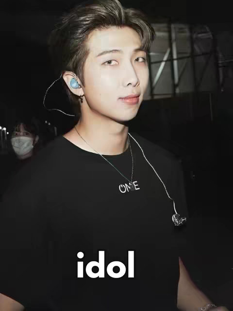 A medium shot featuring a man in a black shirt and silver chain with the word 'ONE' visible. The image is set against a dark background with the text 'idol' overlaid in white at the bottom.