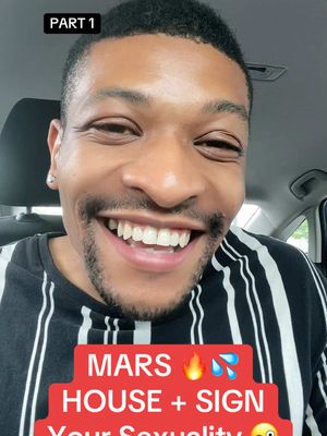 A selfie-style cover image featuring a Black multiracial man smiling brightly from inside the car. He has short, dark hair and a neatly trimmed beard. He wears a black and white striped t-shirt. The background is blurred, with hints of a car interior visible. A red banner with white text overlay covers the lower part, with the text: MARS, a fire emoji, a water emoji, HOUSE + SIGN, and Your Sexuality.