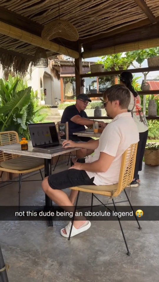 The cover image shows a man sitting at a table with a laptop open, working in an outdoor cafe setting. He's wearing a light pink shirt and casual attire, and a person is walking behind him. The image is bright, with natural light and the overall vibe is casual and relaxed.