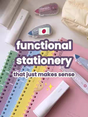 The image is a well-lit overhead shot featuring a collection of Japanese stationery items. A central text overlay reads 'functional stationery that just makes sense' in a rounded, sans-serif font. Below this, a hand with a gesture is featured and a yellow star. The composition includes various notebooks with colored covers, correction tape labeled 'Campus' with a Japanese flag sticker and several white, cylindrical items. The background is a mix of white and pink surfaces. The overall aesthetic is clean, modern, and appealing.