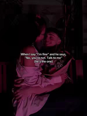 A dimly lit, intimate photo shows two individuals embracing. The foreground features a woman in a light pink top holding a bouquet. The main focus is on a man who appears to be embracing her. The background is dark and indistinct, creating a soft focus on their expressions. Text, written in a clear, white sans-serif font, overlays the image.