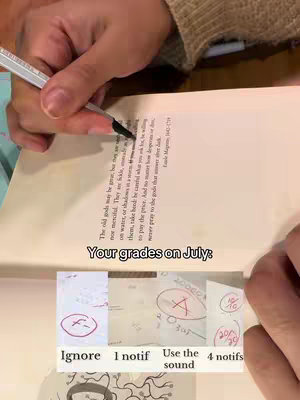The image shows a close-up view of hands interacting with a book and some papers. The hands are holding a pen, which is used to write on an open book. Below the book are multiple post-it notes displaying grades.