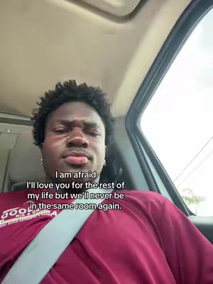 A young Black man is seated inside a car, looking towards the camera with a slightly sad expression. He is wearing a maroon shirt. Text overlayed on the image conveys feelings of love and loss.