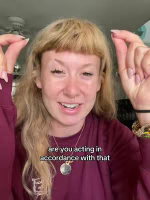 A woman with blonde hair and a fringe is in the frame, with her hands up, seemingly pinching an invisible object. The phrase 'are you acting in accordance with that' is overlaid on the image in a white sans-serif font.