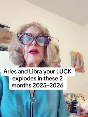 A woman with blonde hair wearing oversized, embellished glasses and a blue top is centered in the shot. A text overlay gives the video's title and content. The background consists of a wall and a hint of objects, suggesting an interior setting. The overall composition is warm-toned with the focal point being the speaker.
