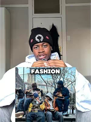 A selfie-style shot of a young Black man with a serious expression, wearing a white hoodie and a black beanie with a white and red logo. Behind him, a section of a room is visible with a white doorframe and a glimpse of a coat, indicating an indoor setting. A smaller image of people in various clothing styles sitting on a bench outside is held up as an overlay with the text "FASHION" on it. The overall composition uses strong contrasts and lighting.