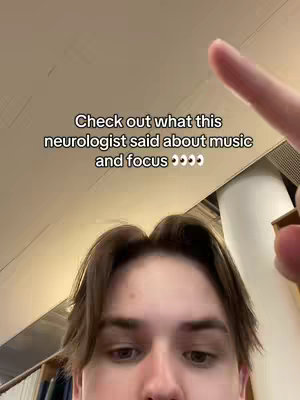 A selfie-style video cover with the subject's face filling the lower portion of the frame. The subject's right arm and index finger point upwards. Above the subject is a text overlay that reads 'Check out what this neurologist said about music and focus.' The background appears to be a light-colored ceiling.