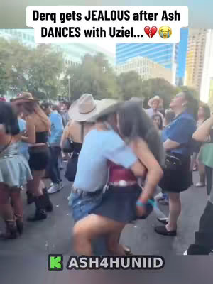The image shows a crowded outdoor setting, likely a festival or street gathering. In the center, two people are embracing, one appearing to be dancing or leaning in closely to the other. The surrounding crowd watches, adding to the public and lively atmosphere. The top of the image has a text overlay stating that someone is jealous. Colors are generally warm and saturated.