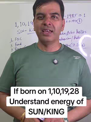 A man is centered in the frame, facing the camera and talking. Behind him is a white board partially visible with text written on it. The man is wearing a solid-colored t-shirt and there is overlaid text at the bottom of the image.