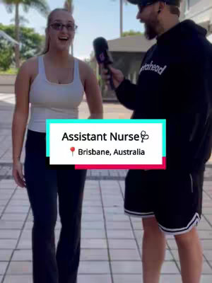 The cover image shows a man in a black hoodie and a woman in a white tank top standing outdoors. The woman is smiling and looking towards the camera, while the man is holding a microphone and looking at her. In the foreground, there is a text overlay with the title 'Assistant Nurse' along with the location 'Brisbane, Australia'. The background is blurred, suggesting a street setting with some greenery.