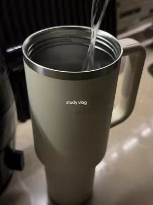 A tall white mug is held, with water pouring into it. The mug is the primary focus. The scene gives off a calm vibe.