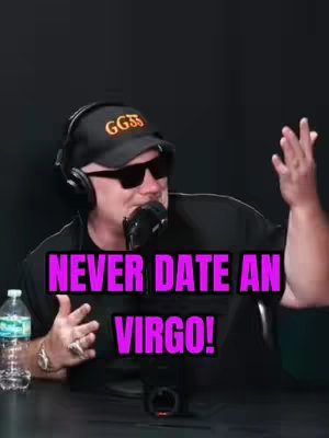 A man in a black hat and sunglasses is speaking into a microphone. The words "NEVER DATE AN VIRGO!" are overlaid in a bright pink text box.