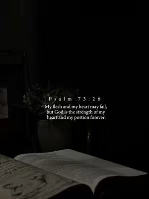 A dark, moody image featuring an open book at the bottom with text overlayed. Above the book, there is a vase with flowers, and the text of a bible verse is displayed in white. The overall composition is dim, with a focus on the text and book.