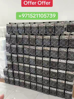 The image shows a large number of cryptocurrency mining machines stacked in rows, filling the frame. The machines are rectangular with mesh fan grates, suggesting they are actively cooling. A red banner at the top reads "Offer Offer," while a green banner below shows a phone number. The setting appears to be an indoor space with a white wall and a light-colored floor. The overall layout emphasizes quantity and a commercial aspect, likely promoting the sale or supply of these mining devices.