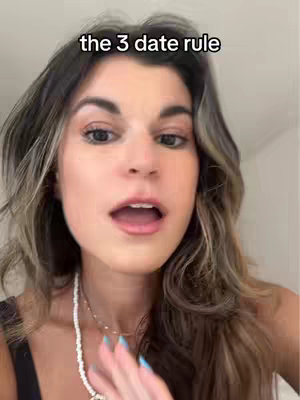 A selfie-style video cover image showcasing a young woman with long, wavy hair that has highlights. She has a fair complexion and is wearing a black top and a silver beaded necklace. Her light blue nails are in focus. The woman’s mouth is open, as if she is speaking. Above her, the text 'the 3 date rule' is placed.