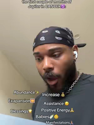 The image shows a Black man looking up with slight surprise, wearing a black bandana and wireless earbuds. Text overlays provide information about Jupiter in Cancer, along with related symbolic themes.