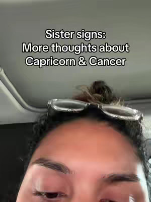 A selfie-style cover image shows an individual with dark hair, clear eyeglasses perched atop their head, and a portion of a ceiling visible in the background. The individual's face is the primary focus. The text overlay reads, "Sister signs: More thoughts about Capricorn & Cancer".