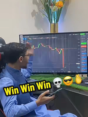 A man is sitting in front of a computer screen displaying a stock chart. He is pointing at the screen with excitement. Overlaid near the screen are emojis like a skull and sunglasses.