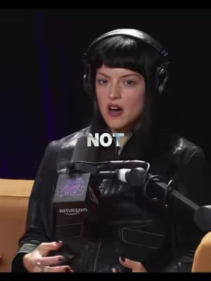 A woman with dark hair wearing headphones and a leather jacket is speaking into a microphone. The word "NOT" is superimposed in white text on the video.