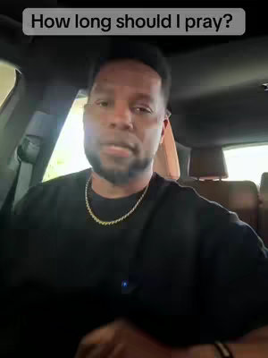 A medium shot inside a car, featuring a man speaking directly towards the viewer. He is wearing a black shirt and a gold chain. The background shows the car's interior and a hint of an outdoor scene through the window. Text overlayed on the top states 'How long should I pray?'.