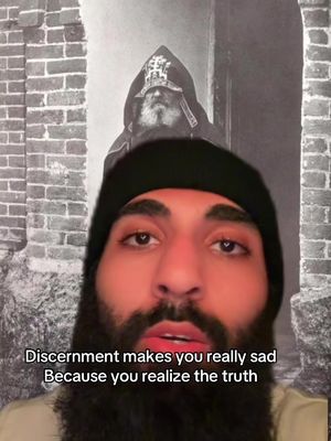 The cover image shows a man with a beard and a black beanie. The background features the upper half of a man in a black cloak and hat. Text at the bottom reads, "Discernment makes you really sad Because you realize the truth."