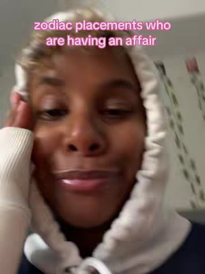 A selfie-style shot features a person with a light-colored hoodie pulled over their head. The person appears to be looking at the camera with a slightly surprised or curious expression. Pink text overlayed on top reads 'zodiac placements who are having an affair'