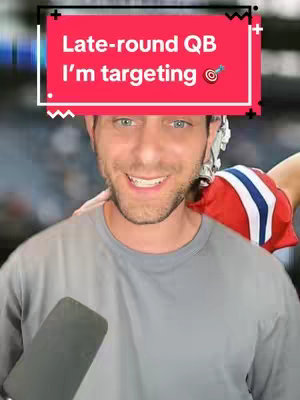 A man with short brown hair smiles at the camera. He wears a gray t-shirt, and a person is seen wearing a football helmet and uniform in the background. Text overlayed on a red rounded rectangle reads: "Late-round QB I'm targeting" with a bullseye emoji.