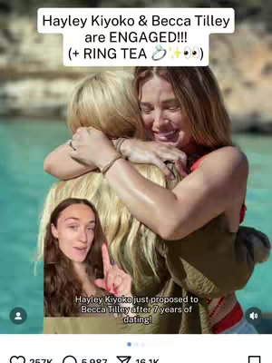 The cover image shows two women embracing on a beach, with one holding the other in a hug. Overlaying this scene is a smaller inset of a woman speaking, and a white text overlay at the top. The general layout is vertical.