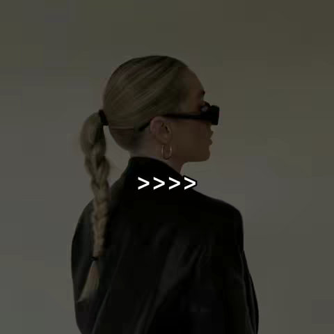The cover image features a woman from the back, with her profile visible, set against a softly lit, neutral background. Her blonde hair is styled in a low ponytail with a braid, and she wears large, dark-framed glasses and hoop earrings. The image has a minimalist aesthetic. Text overlay consisting of four right-angle arrows positioned centrally.
