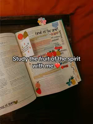 An open bible with highlighted text, with the words 'Fruit of the Spirit' highlighted. Colored sticky notes are on the side, highlighting key information. The text on the top has a sticker on it. The background shows a wooden surface.