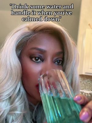 A woman with blonde hair is shown in a close-up shot. She is holding a glass of green liquid up to her mouth as if about to drink it. Overlayed text at the top reads, "Drink some water and handle it when you've calmed down."