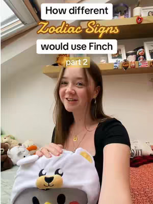 A young woman with long brown hair is holding a white bear-shaped head covering while looking at the camera. Above her head are two rows of shelving, with various items on them. The background is softly lit, which creates a warm and inviting atmosphere.