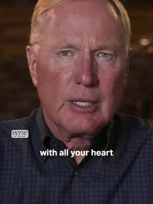 A medium shot of a man with fair skin, blue eyes, and short, light-colored hair, speaking directly into the camera. The background is blurred. The text overlay reads "with all your heart."