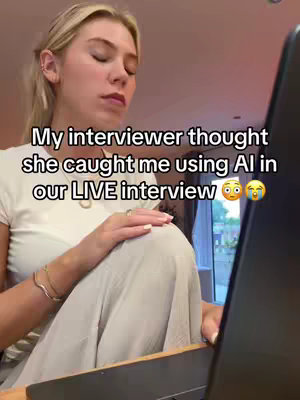 A woman with blonde hair is sitting in front of a laptop. She is wearing a white t-shirt and light colored pants. The text overlay reads, "My interviewer thought she caught me using AI in our LIVE interview".