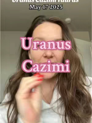 A woman with light hair and red nail polish is centered in a selfie-style video, with the words "Uranus Cazimi" overlaid in a pink, outlined font. Behind her are the words "Uranus Cazimi Taurus May 17 2025". The background is a simple, neutral-toned wall.