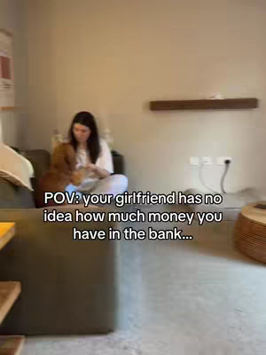 The image shows a woman sitting on a couch in a living room, interacting with a dog. Text overlay adds a 'POV' context, mentioning a girlfriend and money in the bank.
