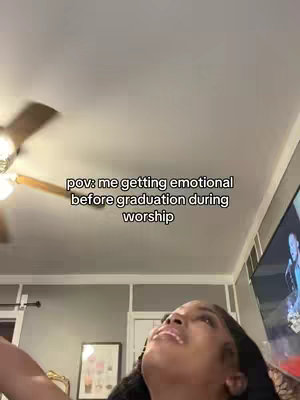 The cover image shows a low-angle shot of a woman looking upwards with an emotional expression. The room has a ceiling fan and the text overlay reads 'pov: me getting emotional before graduation during worship.' The lighting is dim, suggesting an indoor setting.