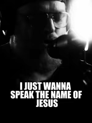 A black and white image featuring a person holding a microphone close to their mouth with text overlayed. The person is partially visible, wearing glasses and a hat. The lighting highlights the person and the microphone, creating a sense of focus. The overlaid text is in bold white, contrasting with the dark background.