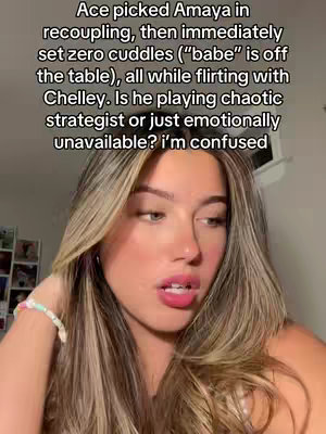 A young woman with long blonde hair looks towards the upper right, touching her hair. There is text on the image talking about a scene from Love Island USA.