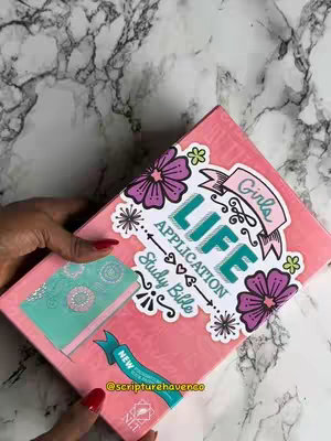 The cover image features a pink Bible held in a person's hands. The Bible is decorated with floral designs and text. The background has a marbled texture. The person's hands are visible, with red nail polish on the nails.