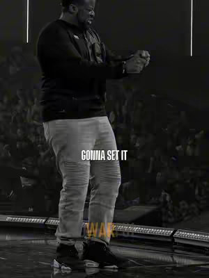 A black and white image of a man in a black long-sleeve shirt and light gray jeans, his hands clasped together in front of him. Two white vertical lines are on the upper part of the frame. The text 'GONNA SET IT' is in the middle with a bottom text partially cut.