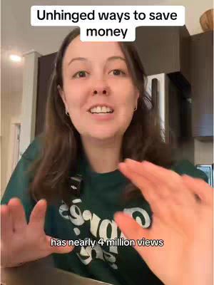 A woman with long brown hair is in a kitchen setting, with upper body framing visible. Text overlays read 'Unhinged ways to save money' at the top and 'has nearly 4 million views' at the bottom. She is smiling at the camera while gesturing to the sides with open hands.