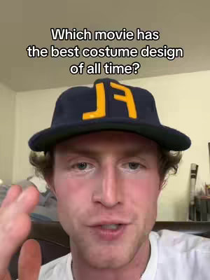 A man with fair skin with a navy blue hat with yellow lettering posing for a video
