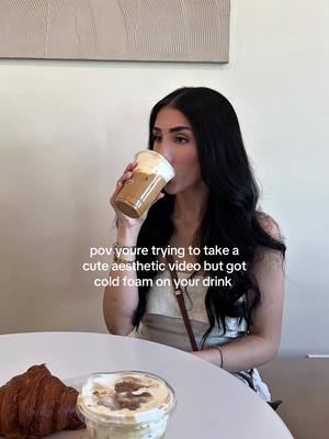A selfie-style image shows a woman drinking from a coffee cup. The woman has long dark hair and is seated at a table that also contains a croissant and a dessert cup. Text overlays the image.