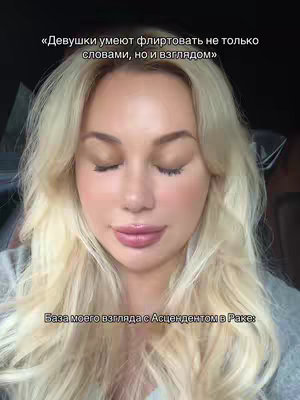 A close-up shot features a light-skinned woman with long, wavy blonde hair. She has pronounced blush and pink lipstick. Her eyes are closed, conveying a thoughtful expression. Text is overlaid at the top and bottom. The overall lighting appears soft.