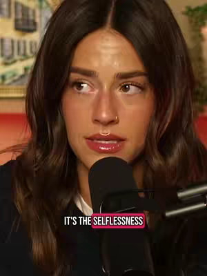 The cover image features a close-up of a woman with long, wavy brown hair looking off to the side. Her lips are slightly parted. A microphone is positioned in front of her. Text overlayed near the bottom reads: "IT'S THE SELFLESSNESS."